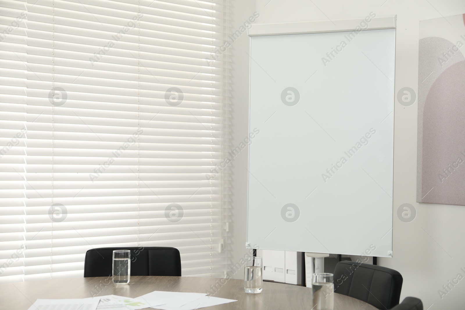 Photo of Flip chart, wooden table and chairs in conference room. Mockup for design