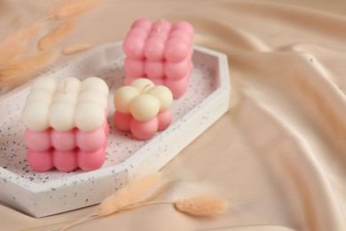 Photo of Beautiful bubble candles and dry spikes on beige fabric, closeup