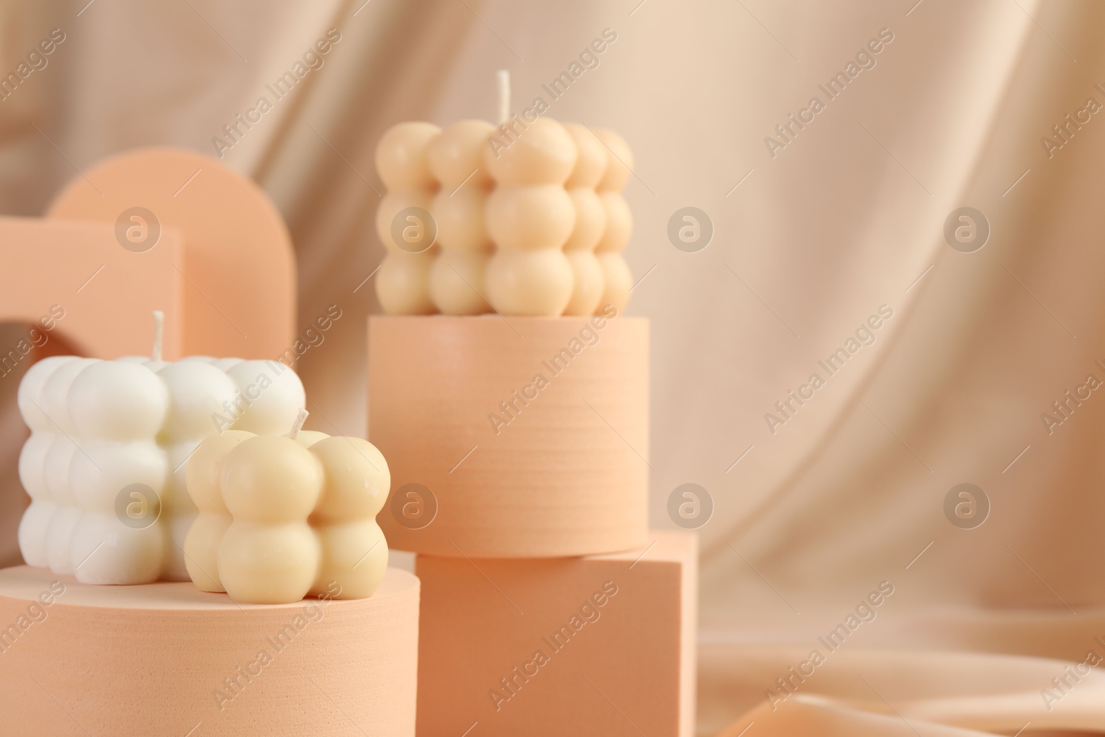 Photo of Beautiful bubble candles and geometric figures on beige fabric, closeup. Space for text