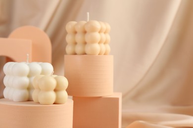 Photo of Beautiful bubble candles and geometric figures on beige fabric, closeup. Space for text