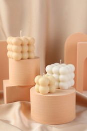 Photo of Beautiful bubble candles and geometric figures on beige fabric