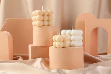 Photo of Beautiful bubble candles and geometric figures on beige fabric