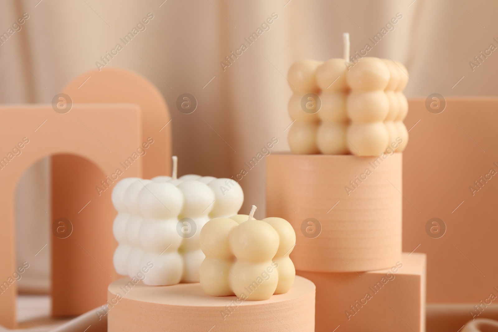 Photo of Beautiful bubble candles and geometric figures on fabric, closeup