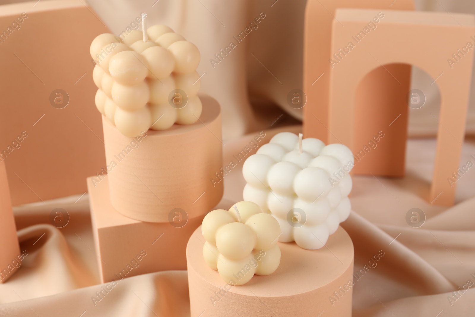 Photo of Beautiful bubble candles and geometric figures on beige fabric