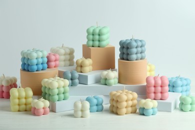 Photo of Many beautiful bubble candles and podiums on white table