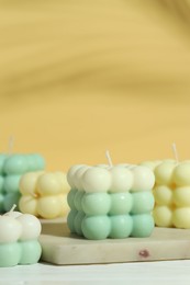 Photo of Beautiful bubble candles on white wooden table, closeup