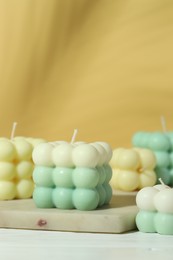 Photo of Beautiful bubble candles on white wooden table, closeup