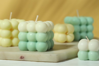 Beautiful bubble candles on white wooden table, closeup