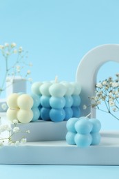 Photo of Beautiful bubble candles, gypsophila flowers and geometric figures on light blue background