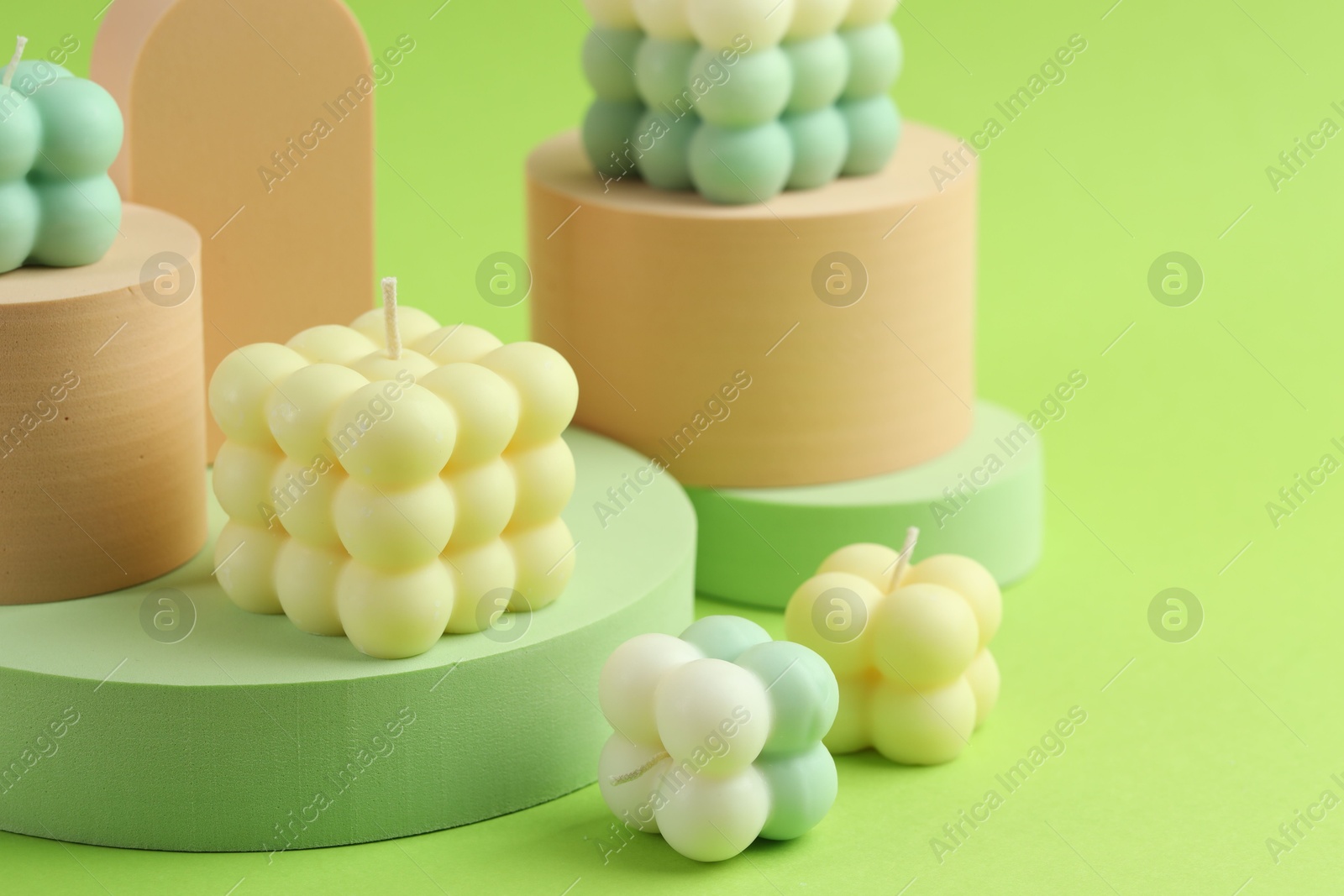 Photo of Beautiful bubble candles and geometric figures on green background, closeup