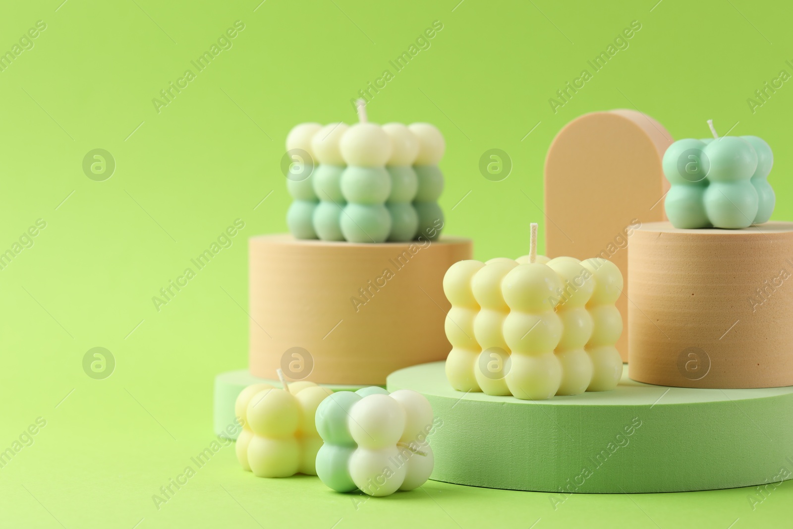 Photo of Beautiful bubble candles and geometric figures on green background