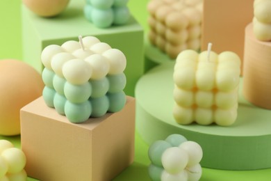 Photo of Beautiful bubble candles and geometric figures on green background, closeup