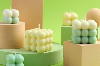 Photo of Beautiful bubble candles and geometric figures on green background, closeup