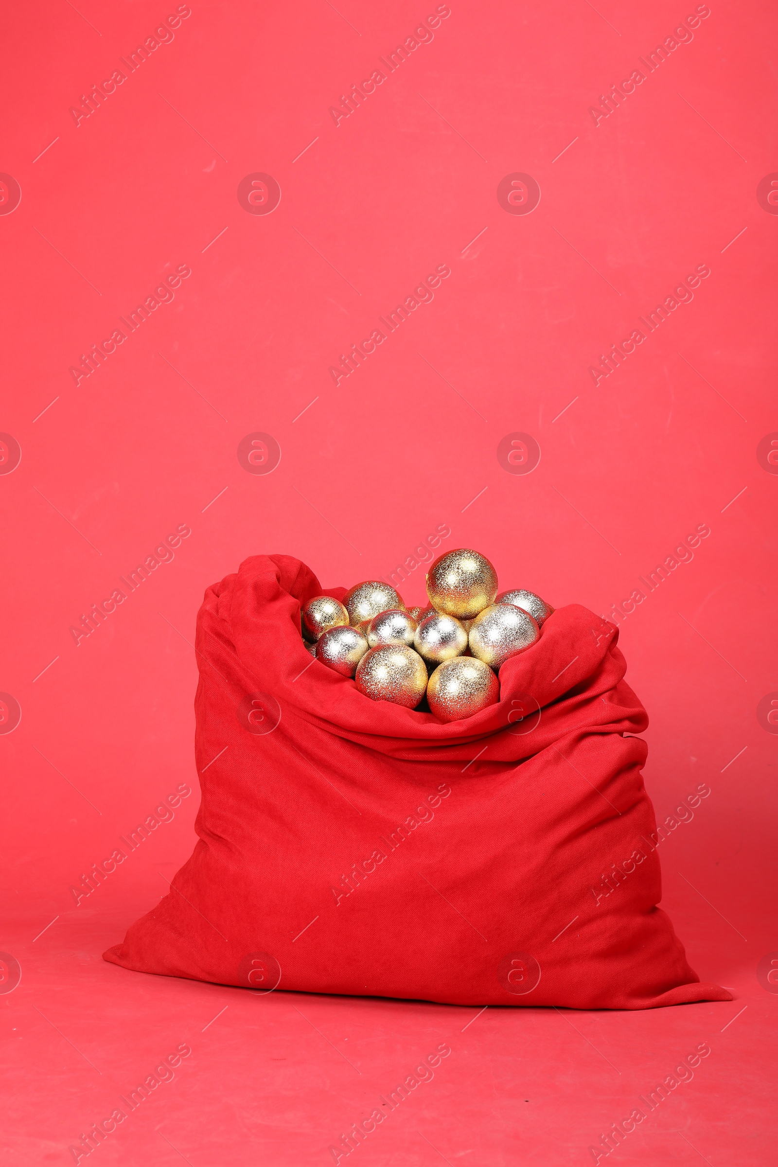 Photo of Santa Claus bag with baubles on red background