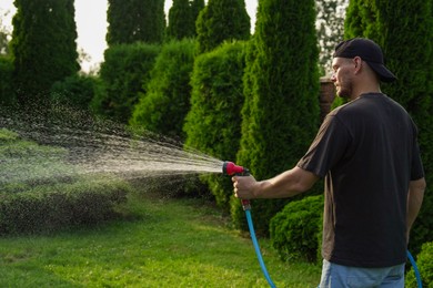 Man watering lawn with hose in backyard