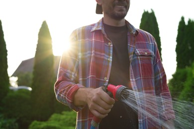 Photo of Man watering lawn with hose in backyard, closeup