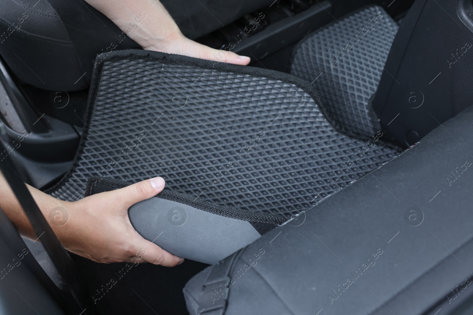 Photo of Man taking grey rubber car mat from auto, closeup