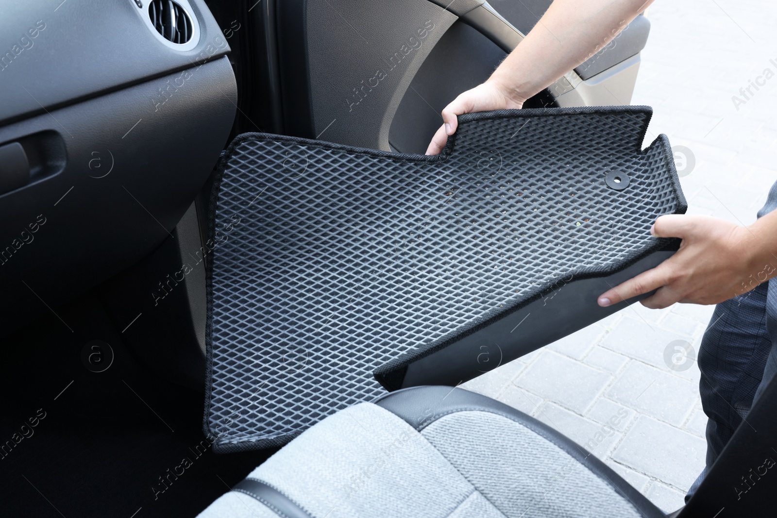 Photo of Man taking grey rubber car mat from auto, closeup