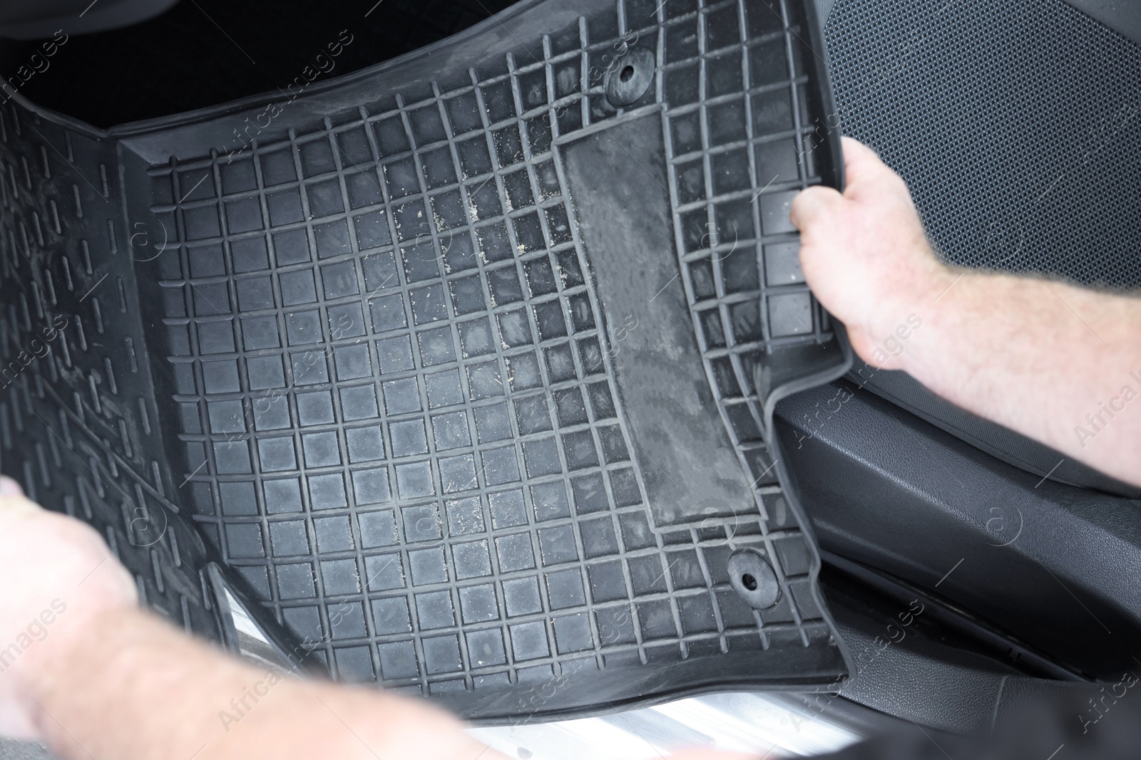 Photo of Man taking black rubber car mat from auto, closeup