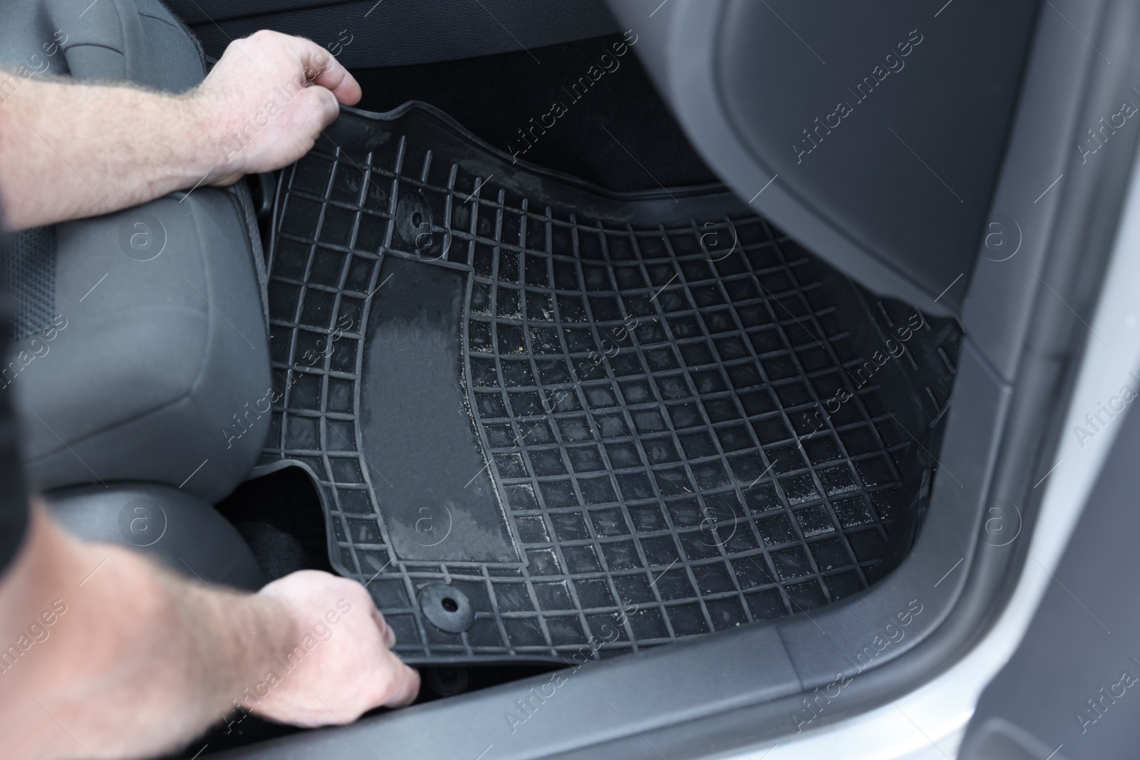 Photo of Man taking black rubber car mat from auto, closeup