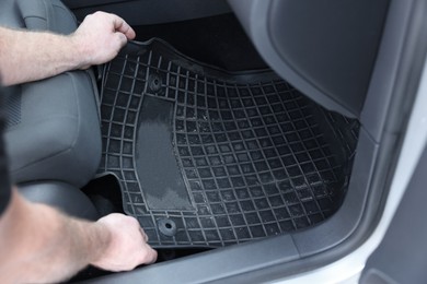 Photo of Man taking black rubber car mat from auto, closeup