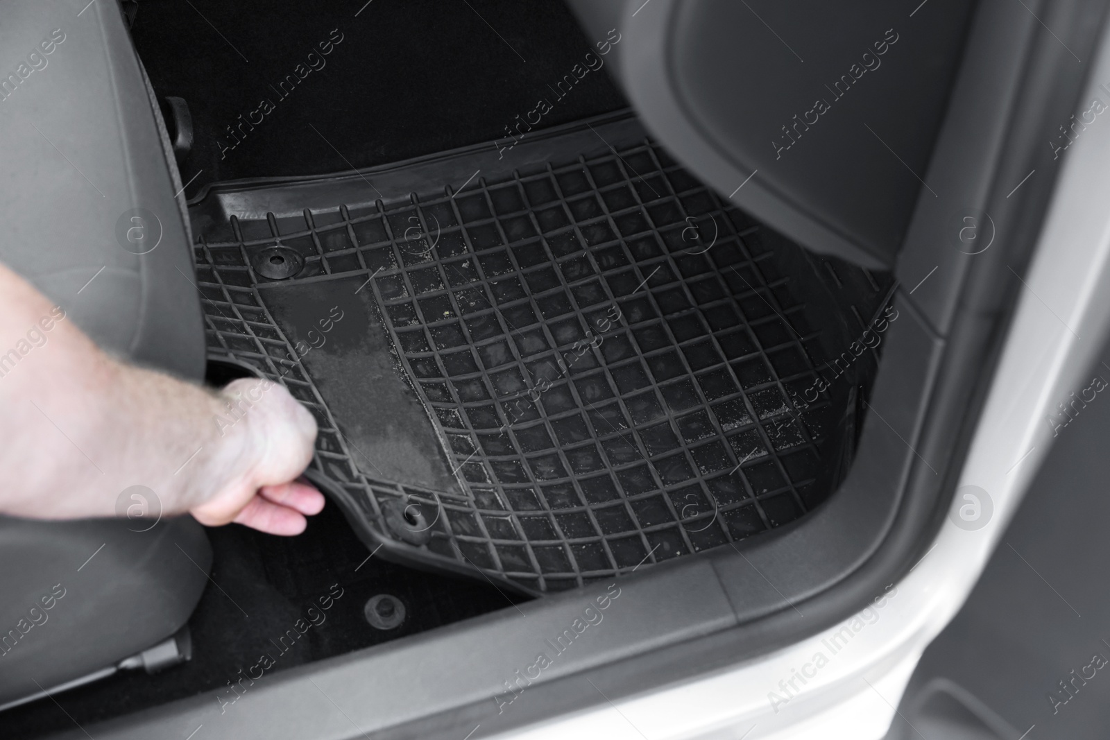 Photo of Man taking black rubber car mat from auto, closeup