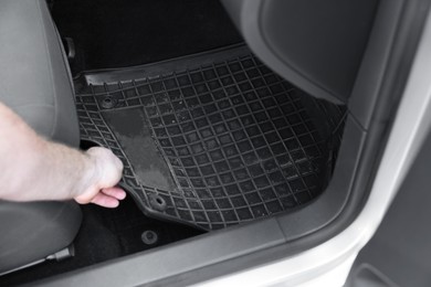 Photo of Man taking black rubber car mat from auto, closeup