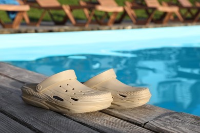 Stylish shoes on wooden deck near outdoor swimming pool