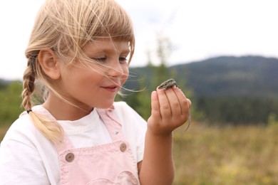 Happy little girl holding small lizard outdoors