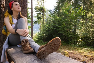 Photo of Young hiker sitting on wooden bench in forest