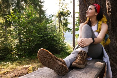 Photo of Young hiker sitting on wooden bench in forest