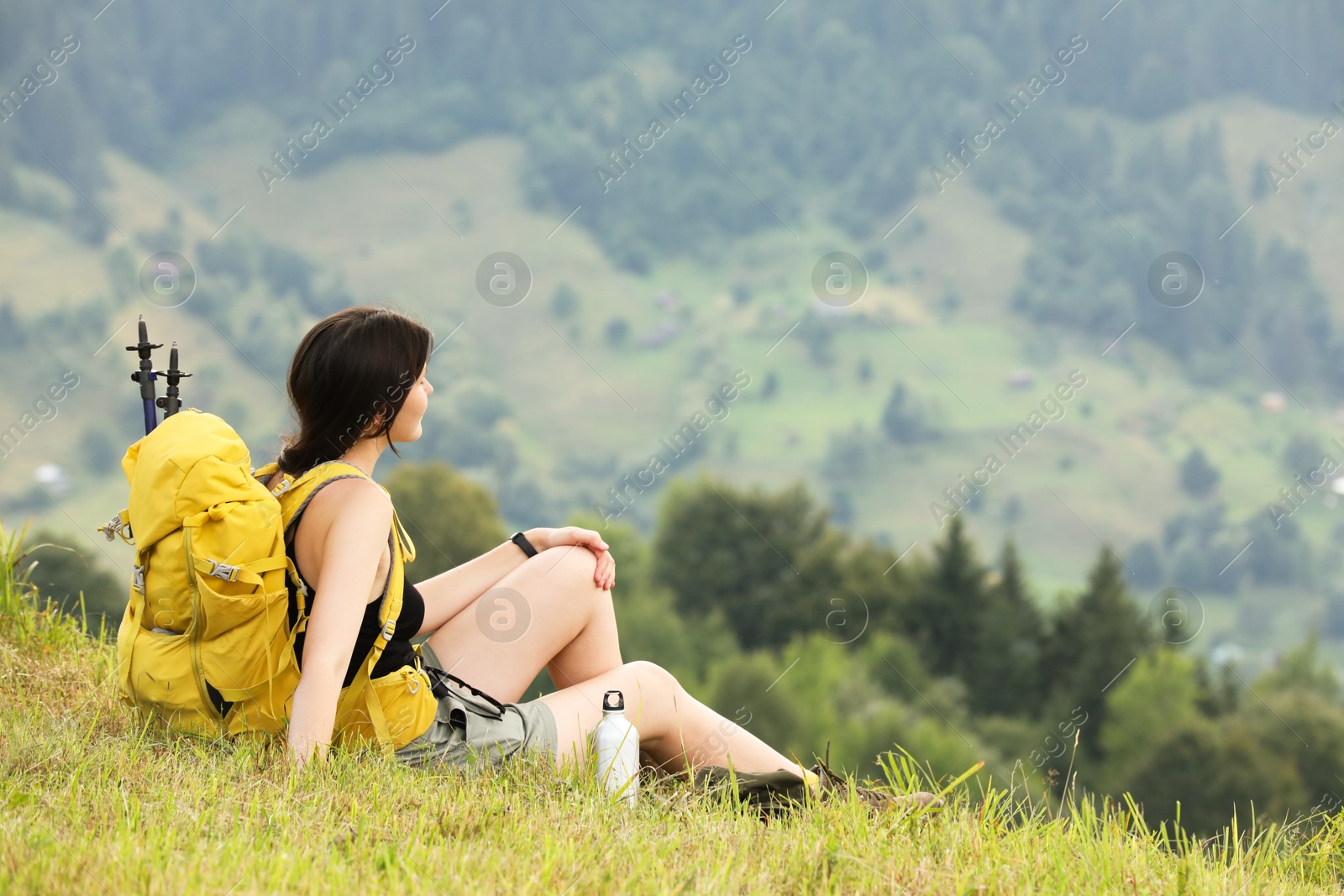 Photo of Young hiker with backpack in mountains, space for text