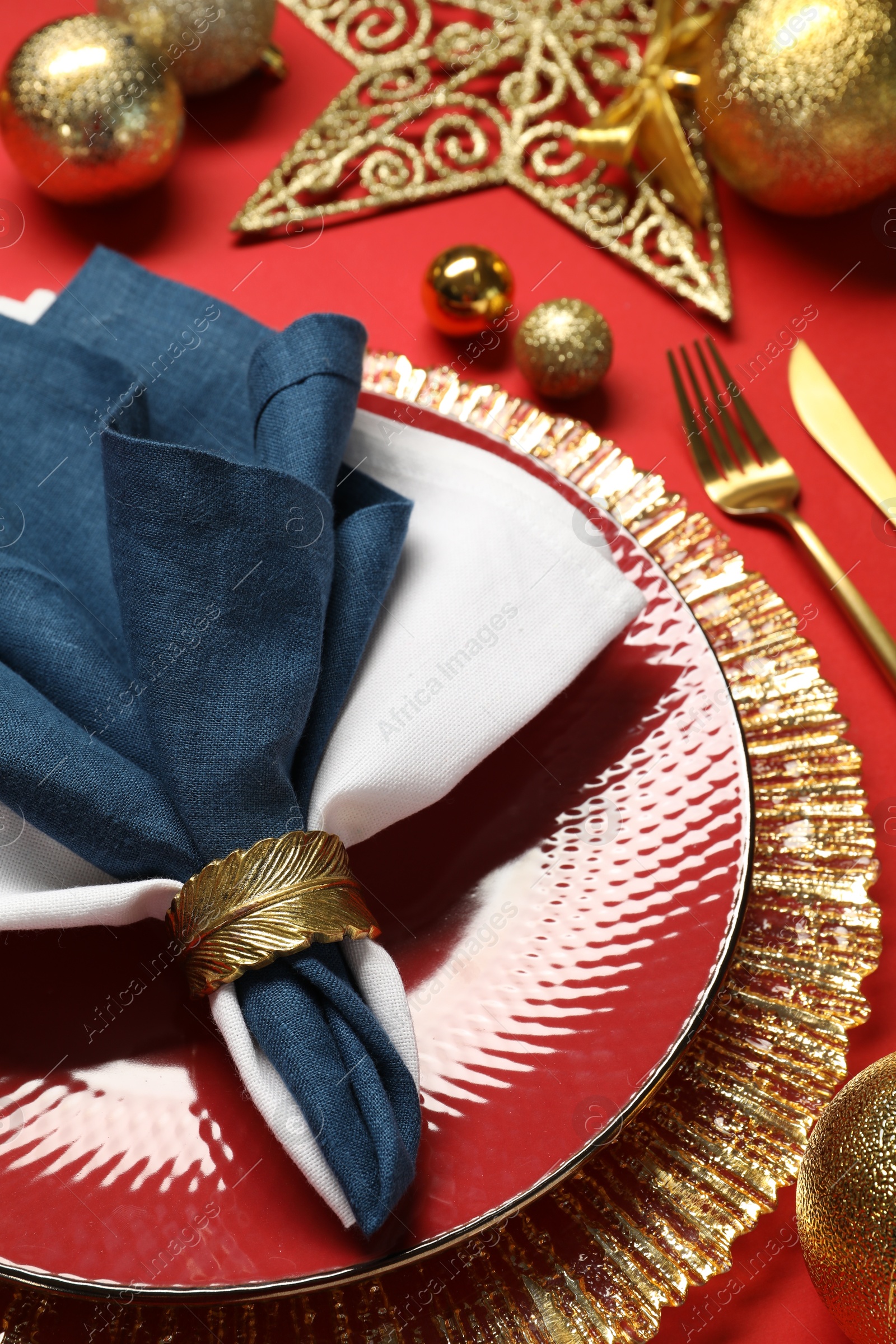 Photo of Christmas place setting with festive decor on red table, closeup