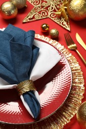 Photo of Christmas place setting with festive decor on red table, closeup