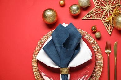 Photo of Christmas place setting with festive decor on red table, flat lay. Space for text