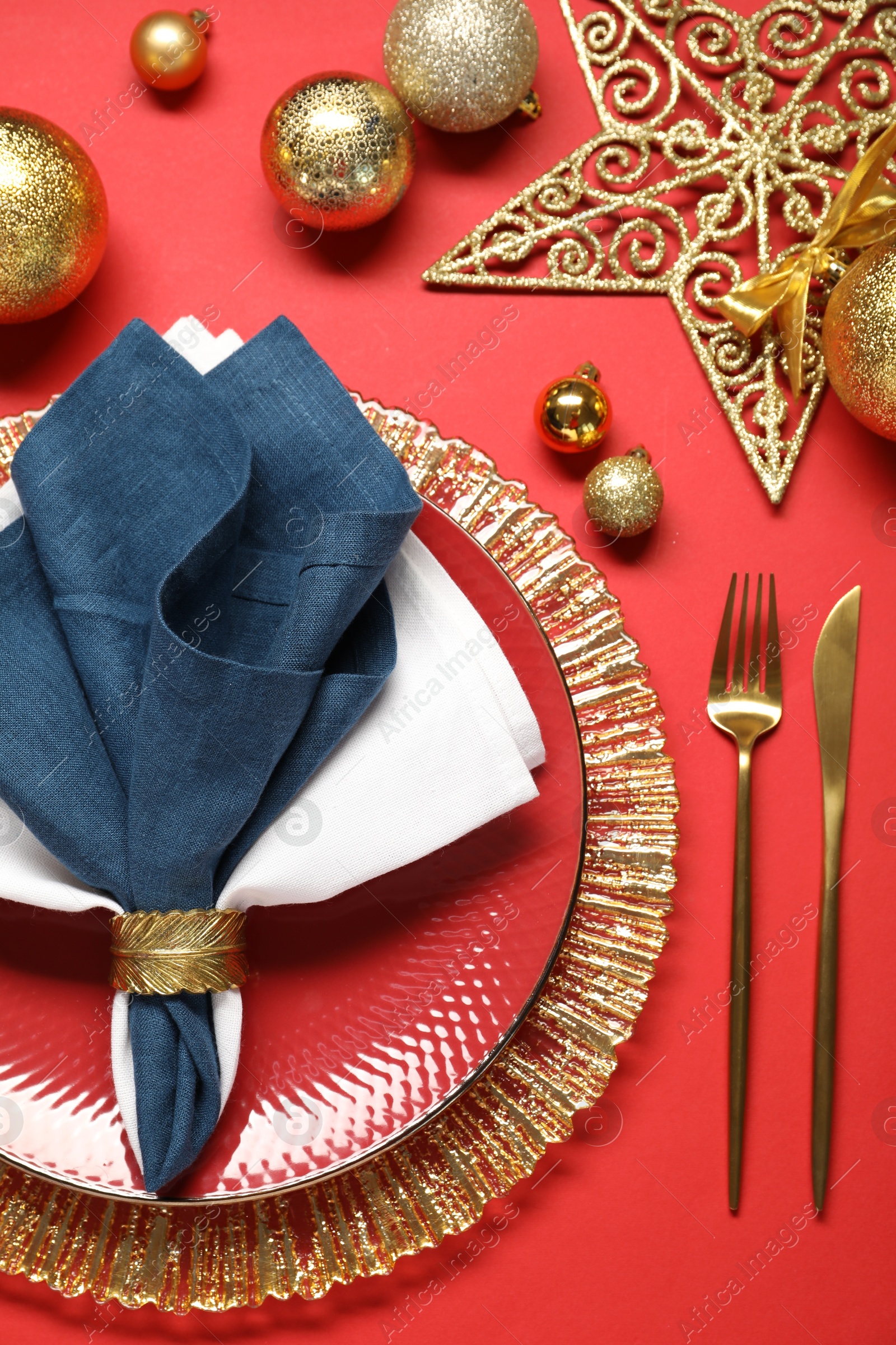 Photo of Christmas place setting with festive decor on red table, flat lay