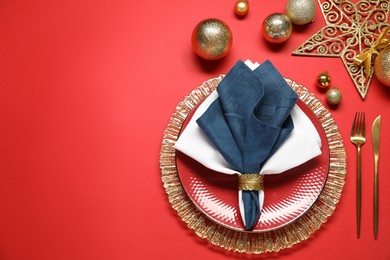 Photo of Christmas place setting with festive decor on red table, flat lay. Space for text