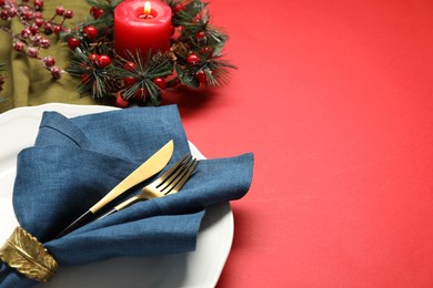 Photo of Christmas place setting with festive decor on red table, closeup. Space for text