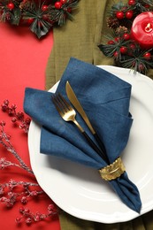 Photo of Christmas place setting with festive decor on red table, flat lay