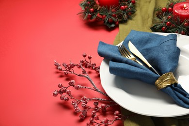 Photo of Christmas place setting with festive decor on red table, closeup. Space for text