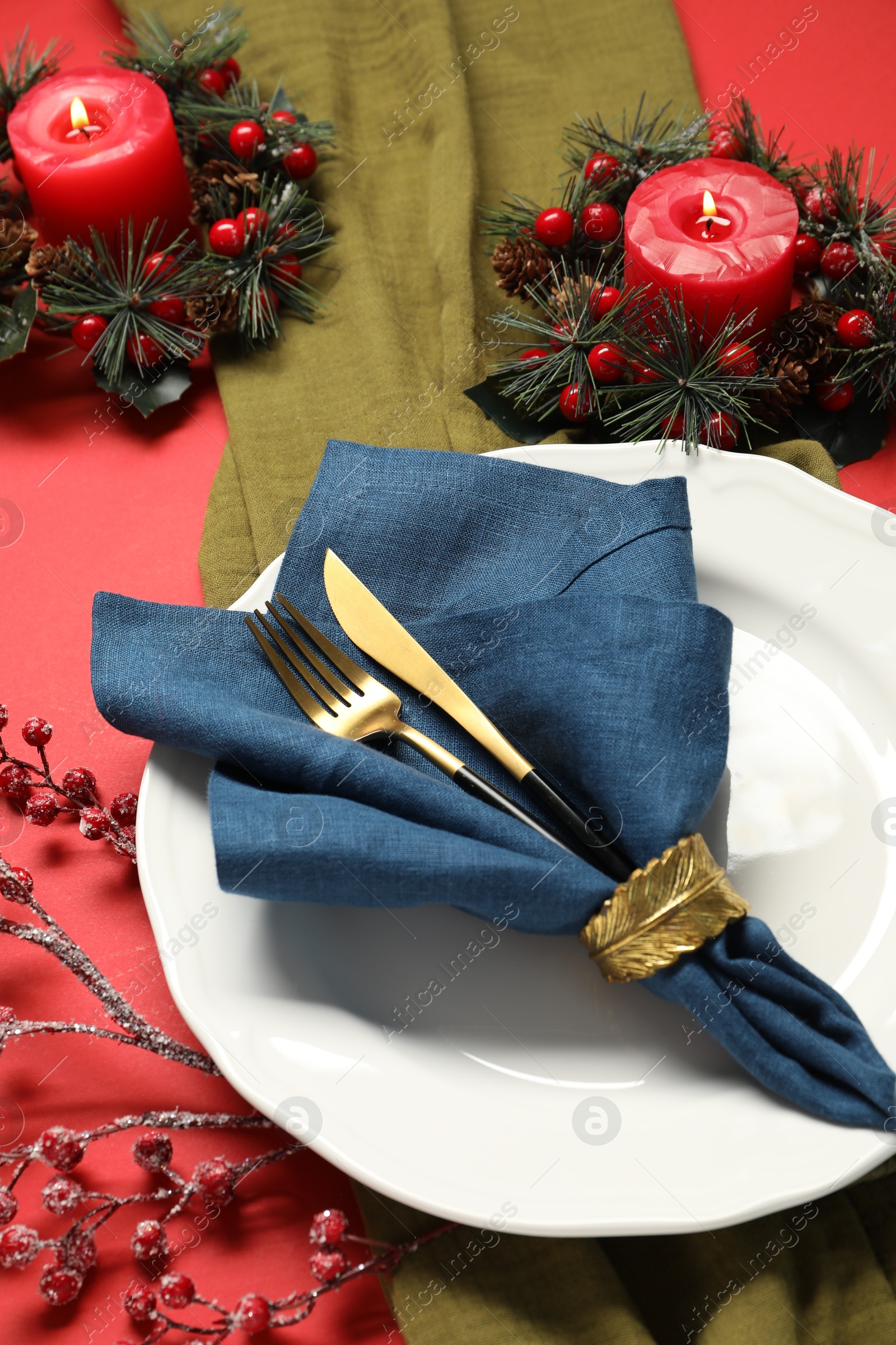 Photo of Christmas place setting with festive decor on red table