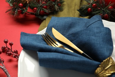 Photo of Christmas place setting with festive decor on red table, closeup