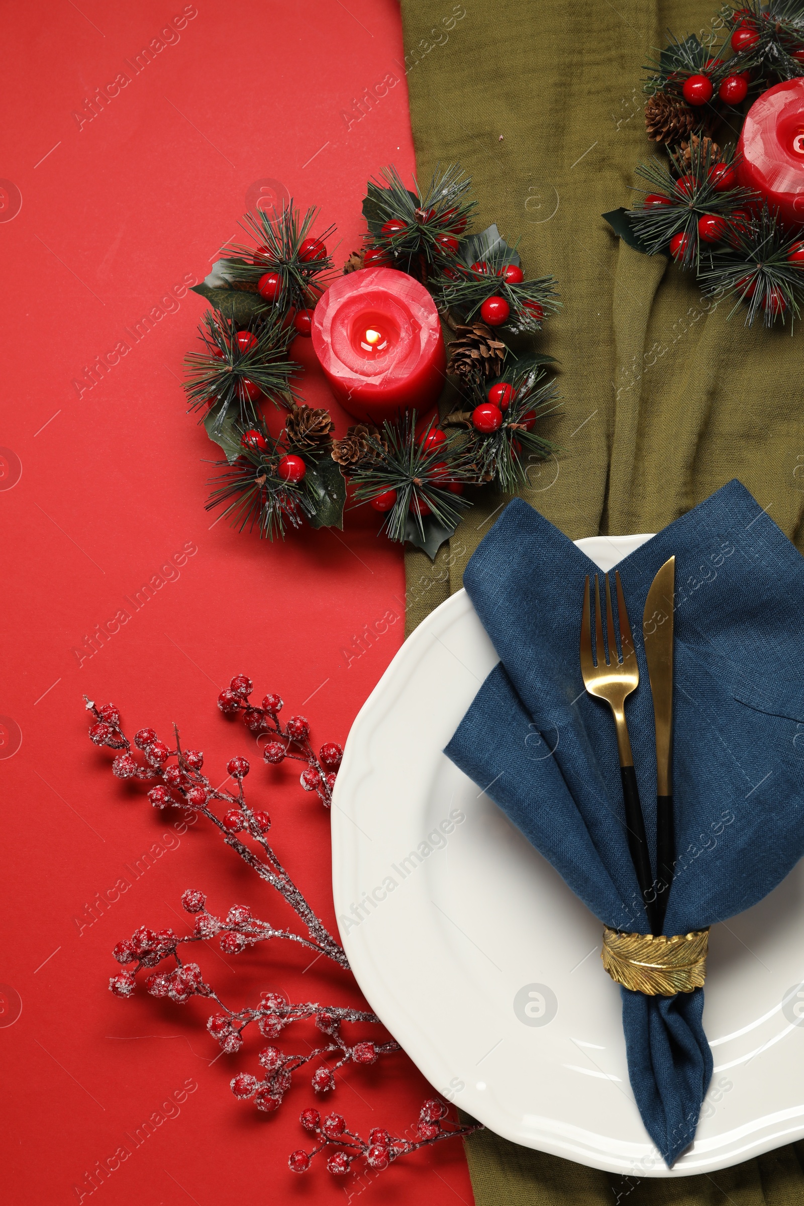 Photo of Christmas place setting with festive decor on red table, flat lay