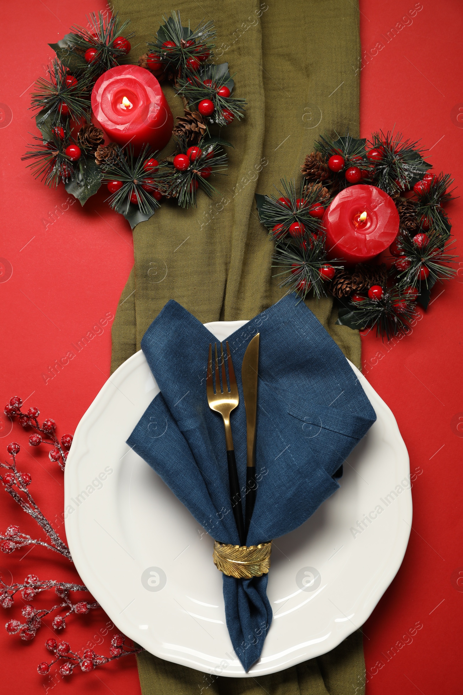 Photo of Christmas place setting with festive decor on red table, flat lay