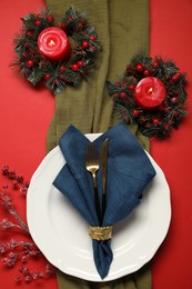 Photo of Christmas place setting with festive decor on red table, flat lay