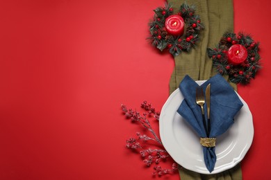 Photo of Christmas place setting with festive decor on red table, flat lay. Space for text