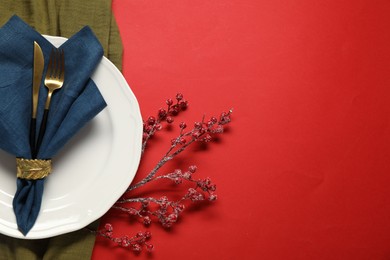 Photo of Christmas place setting with festive decor on red table, flat lay. Space for text