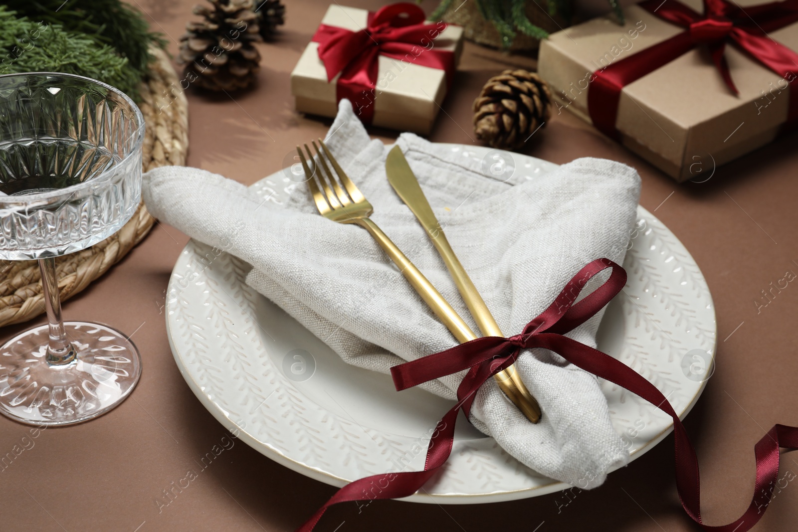 Photo of Christmas place setting with festive decor on brown table, closeup