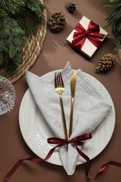 Photo of Christmas place setting with festive decor on brown table, flat lay