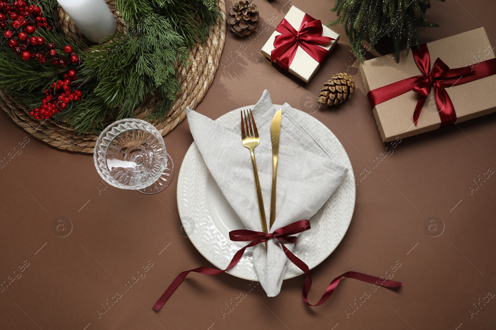 Photo of Christmas place setting with festive decor on brown table, flat lay